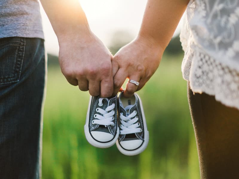 Prospective parents holding baby shoes, representing fertility care